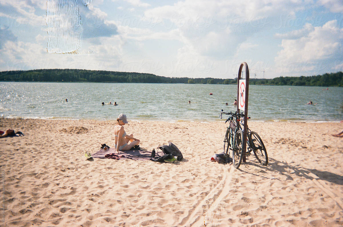 Woman sitting on sandy beach during bicycle ride trip