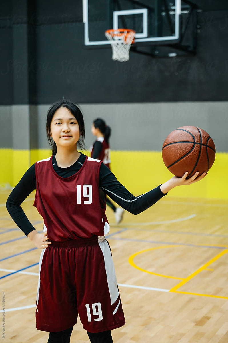 Teenage girl wearing basketball uniforms and looking at camera