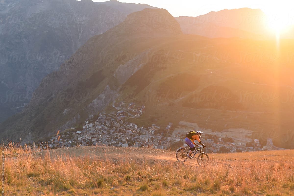 Male biker riding downhill mountain singletrack in the golden hour