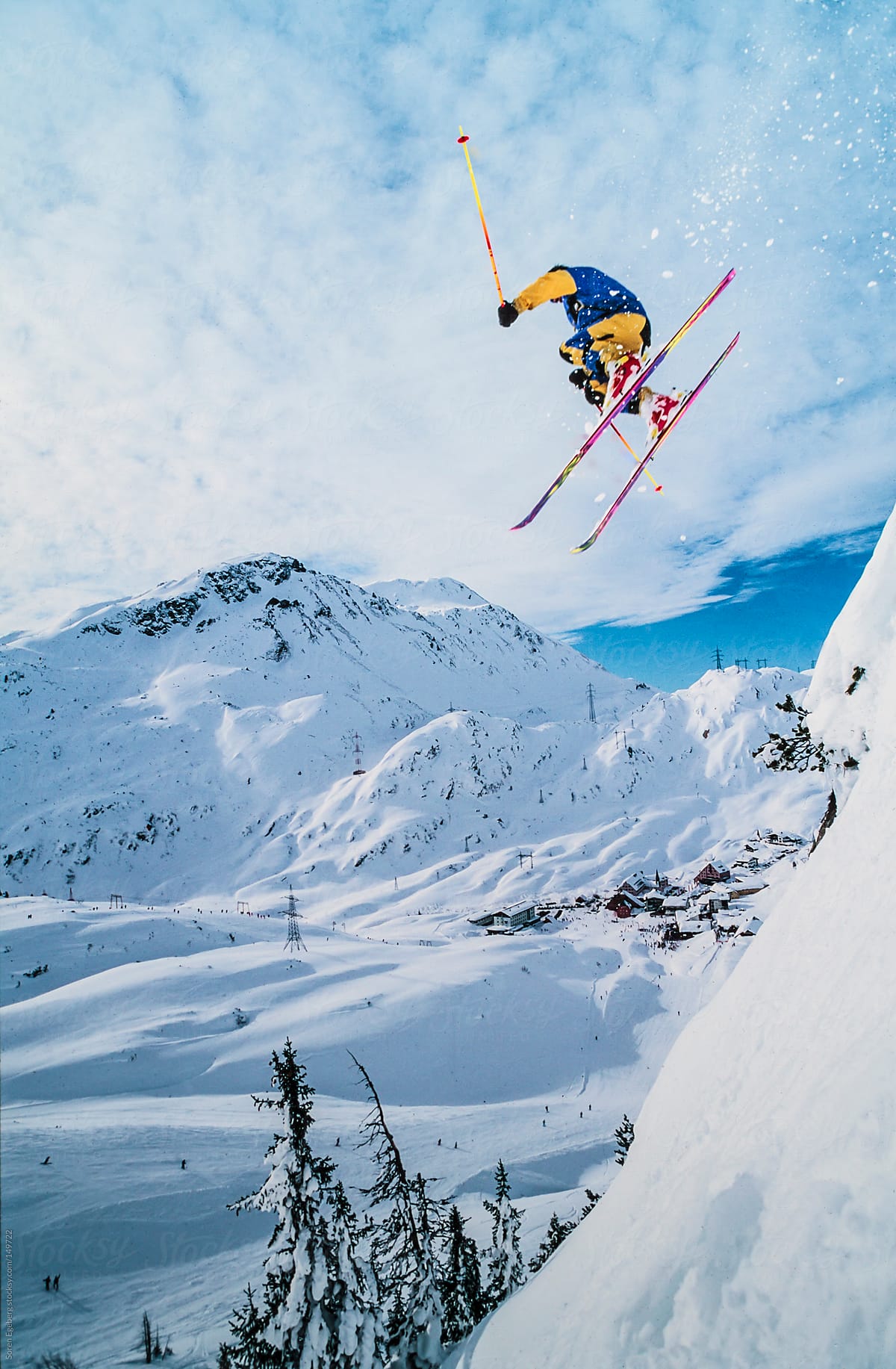 Skier jumping off snow cornice in winter mountain landscape