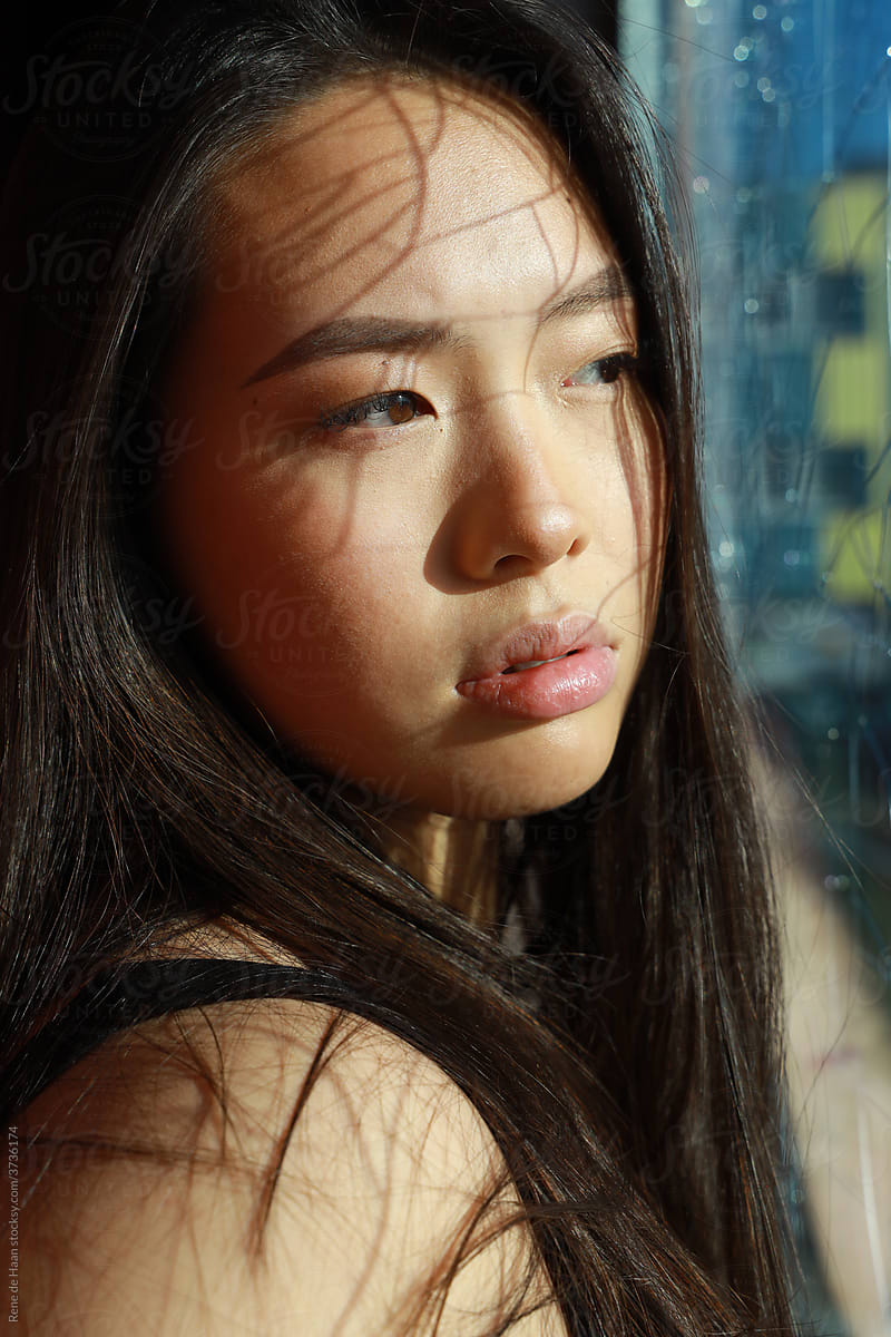 young Chinese woman behind broken glass window