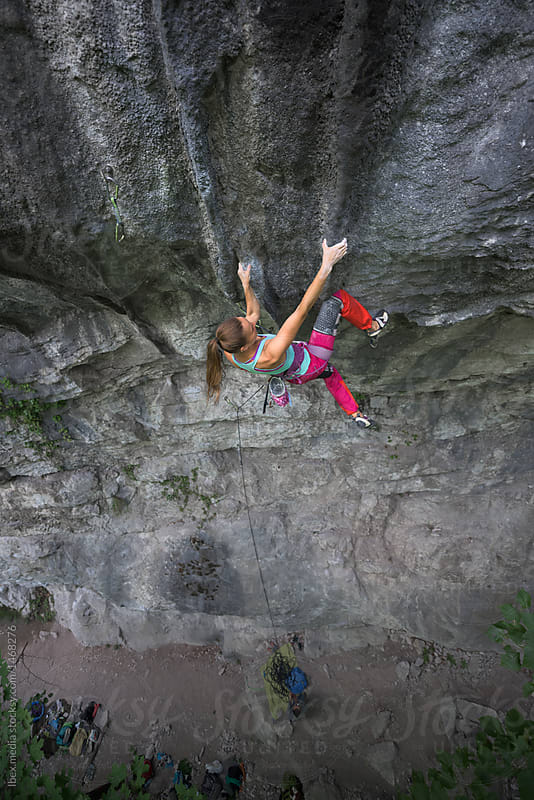 Determined young caucasian woman rock climbing on rock face