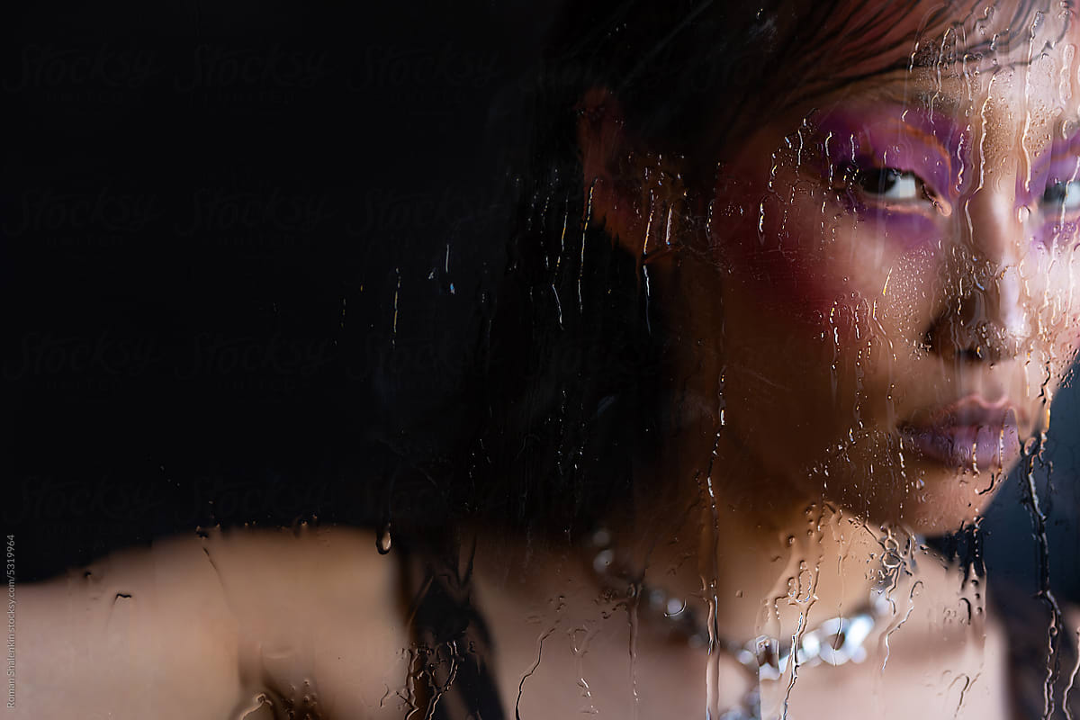 Asian woman with fashion pink makeup through wet glass