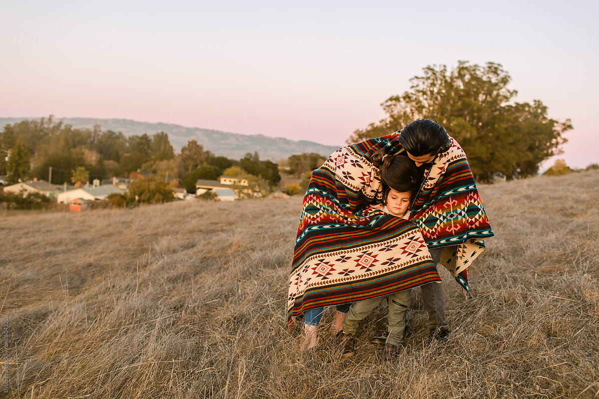 Family warming-up on ethnic blanket in regional park
