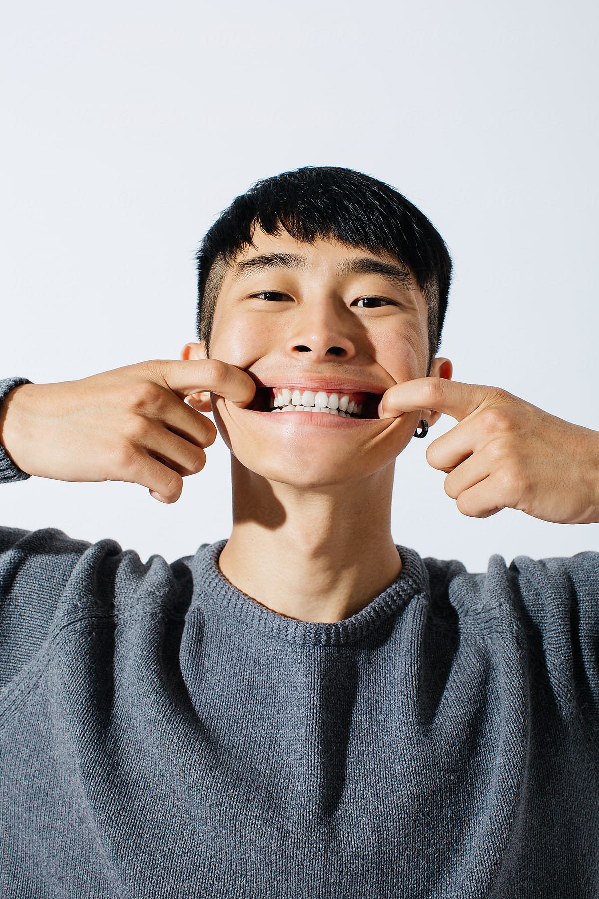 Portrait of a young asian man making funny face over white background.