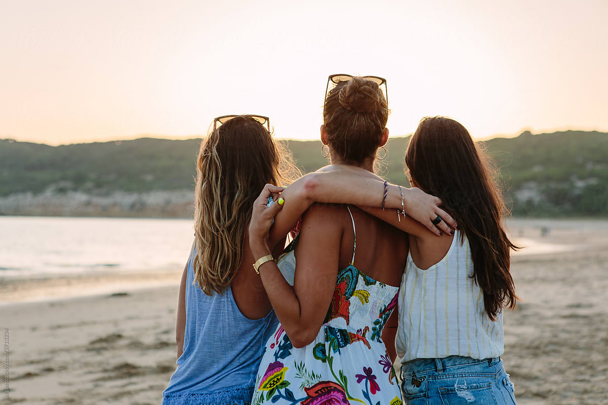 Three friends watch the sunset from behind