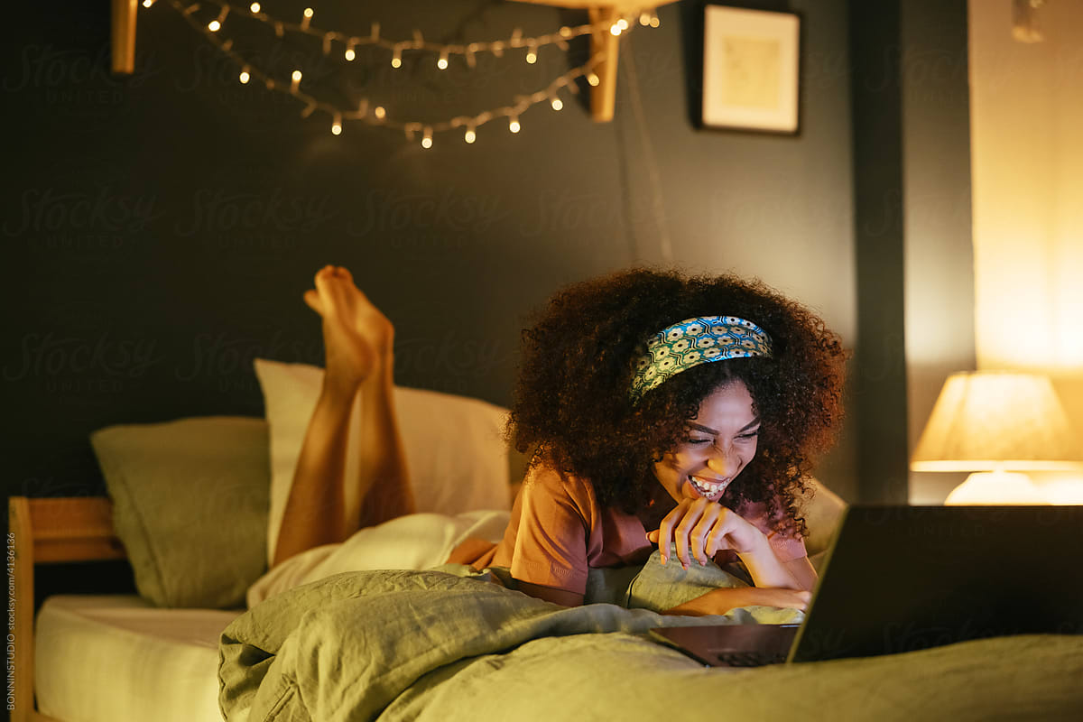Woman watching movie on laptop in bedroom