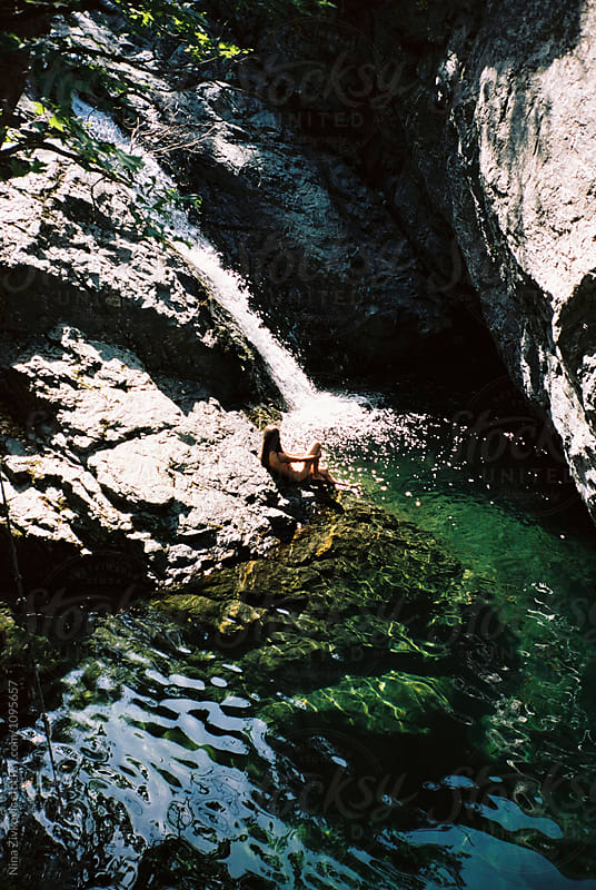 A young girl sitting by the waterfall.