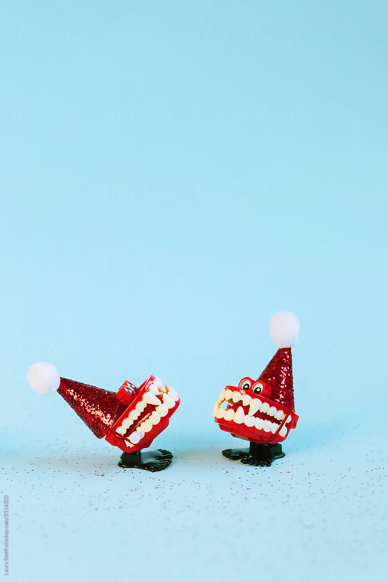 Two fake vampire teeth wind up toys wearing glittery santa hats