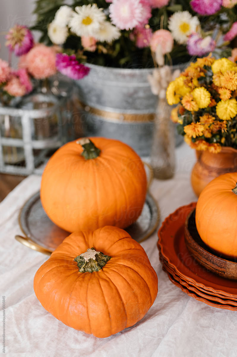 Pumpkins near bouquets on table