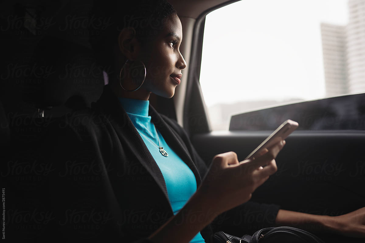 Afro woman using mobile phone into the car