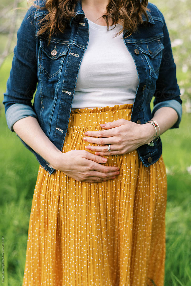 unrecognizable detail shot of pregnant woman in yellow skirt