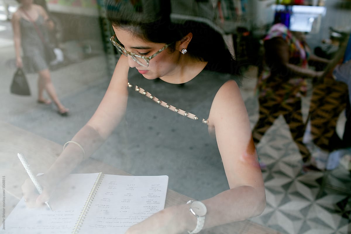 Woman writes in notebook in coffee shop