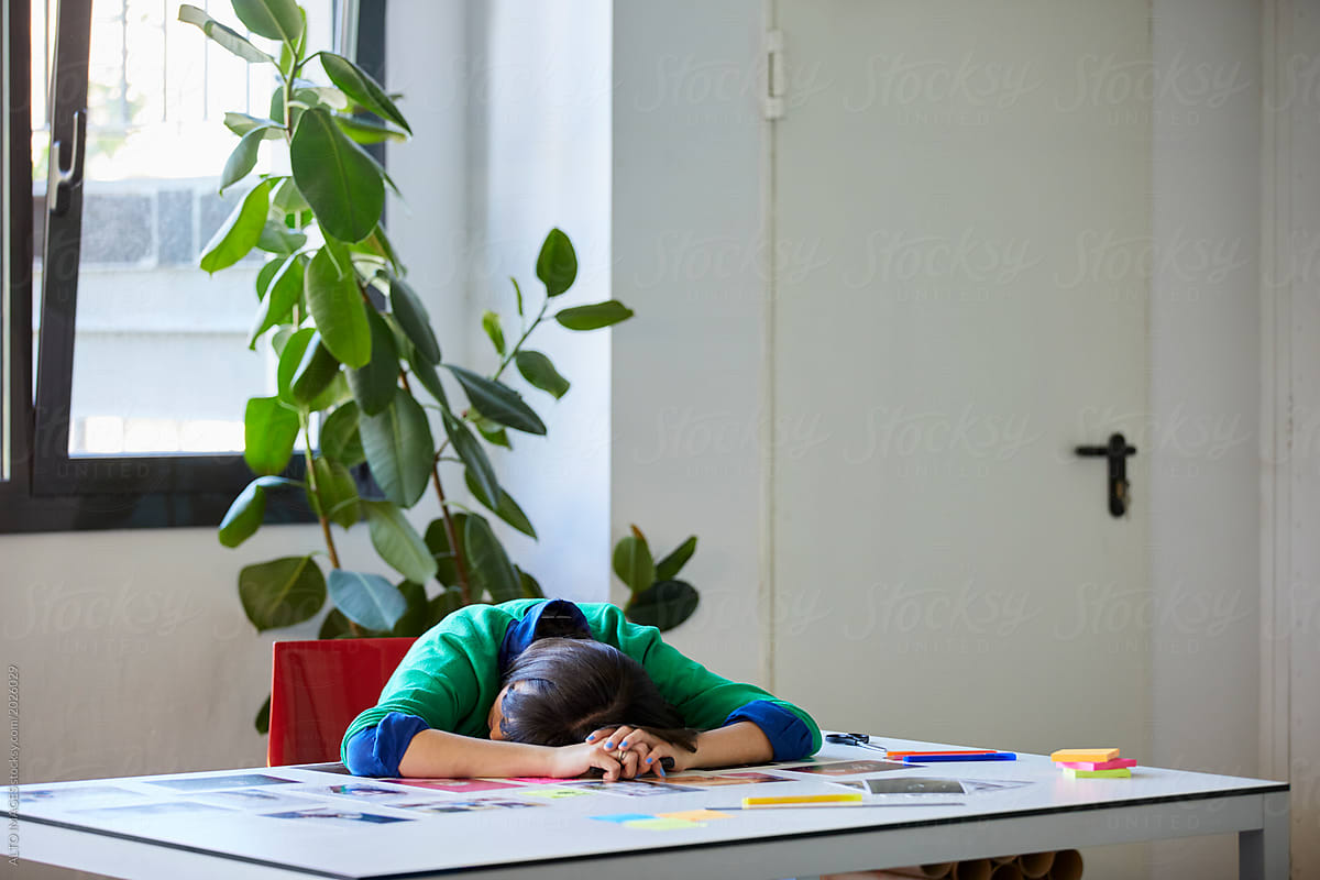 Exhausted Executive Lying With Head Down On Table By Alto Images