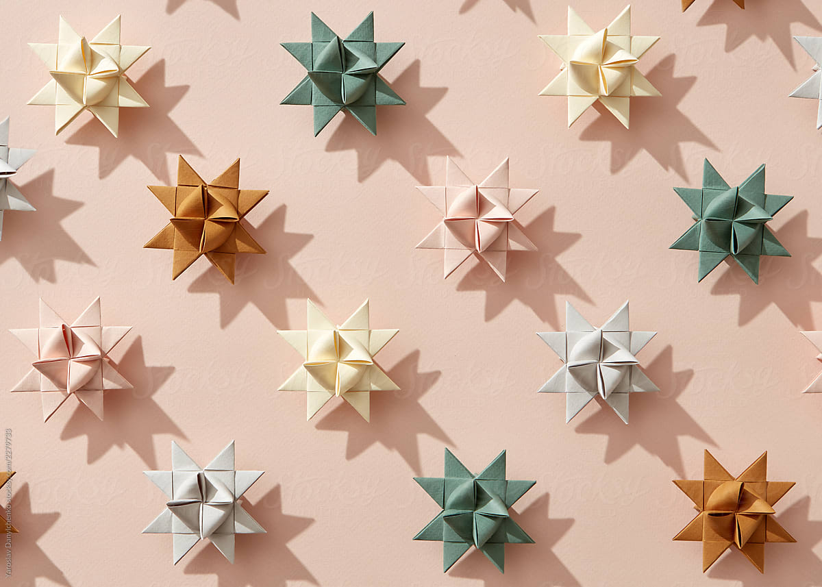 Origami stars made of paper on beige background with shadows. Creative New Year pattern. Flat lay