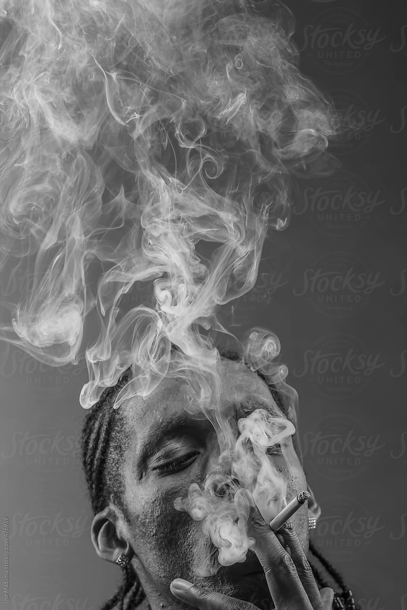 black man smokes a cigarette, thick smoke
