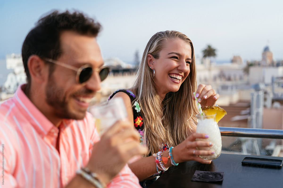 Cheerful couple with cocktails on rooftop