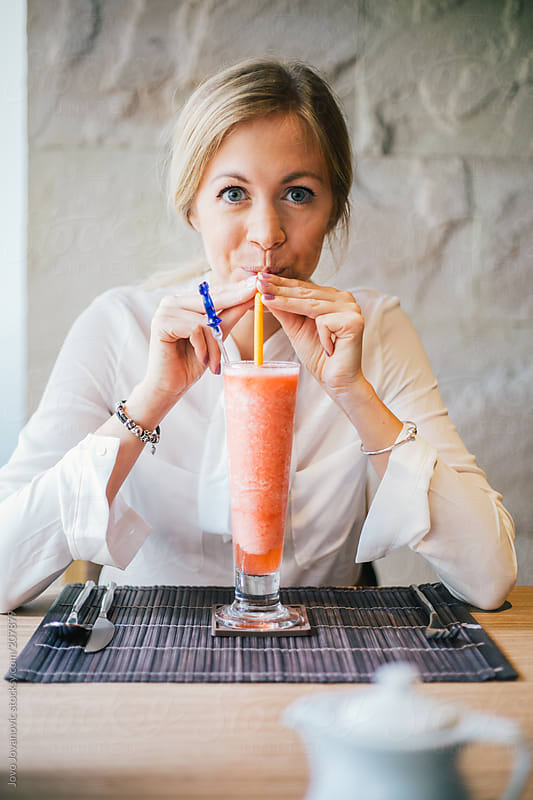 Cute Blonde Girl Drinking Smoothie In A Restaurant By Jovo Jovanovic