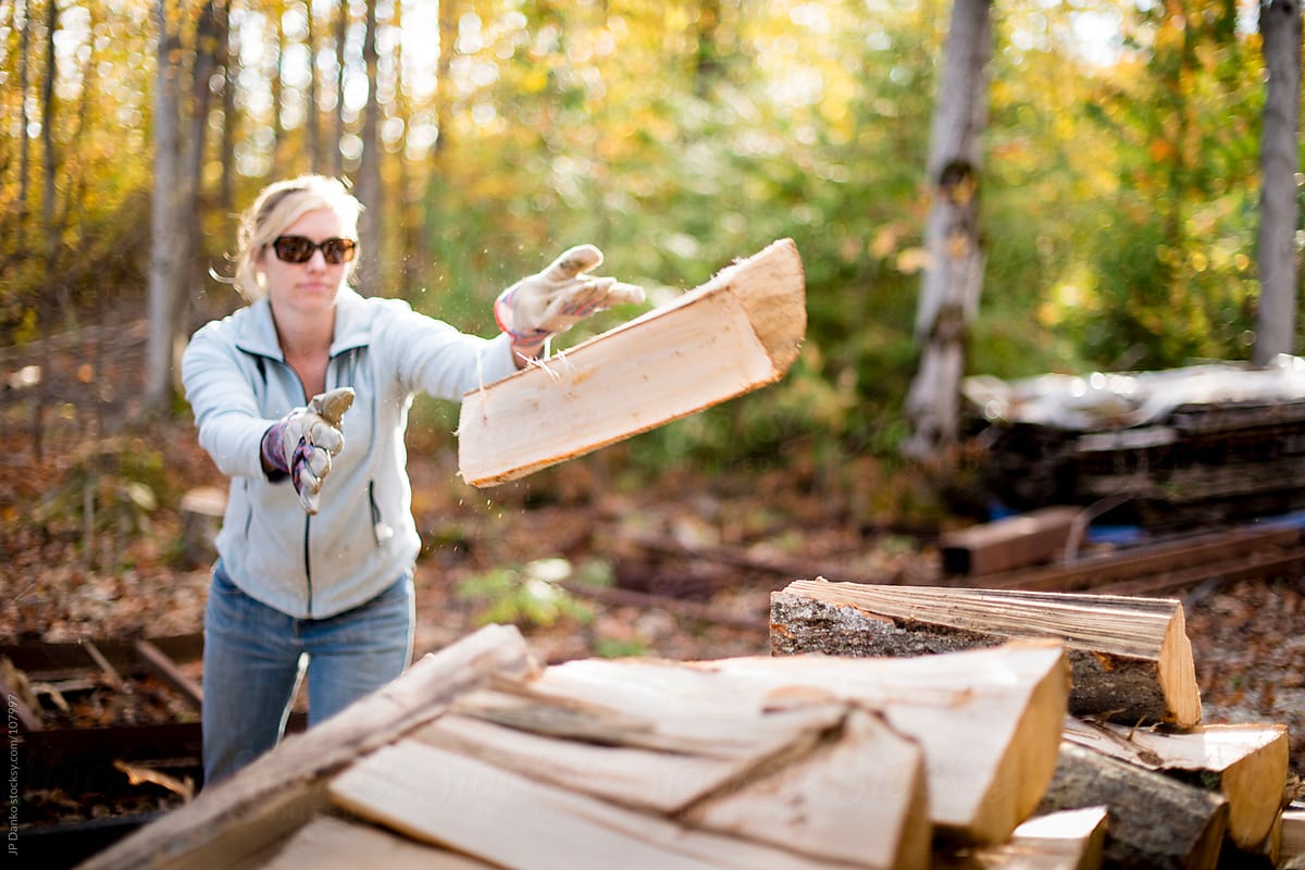 Woman Stacking Winter Firewood for In Autumn at Cottage
