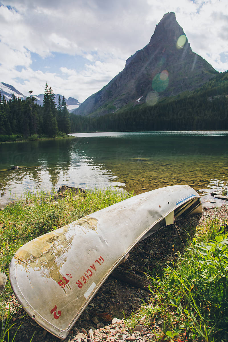 A rusted canoe on the shore of a mountain lake