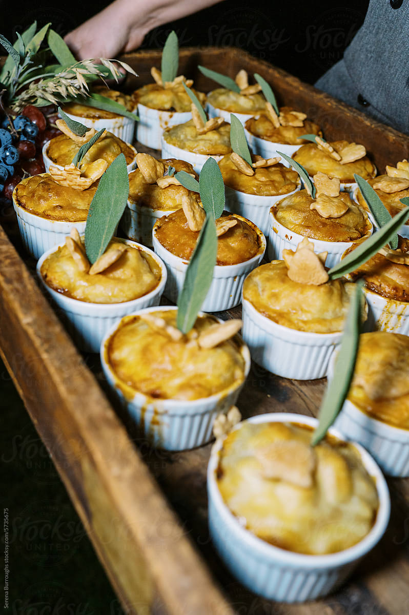 individual pot pies held by chef at dinner party at night