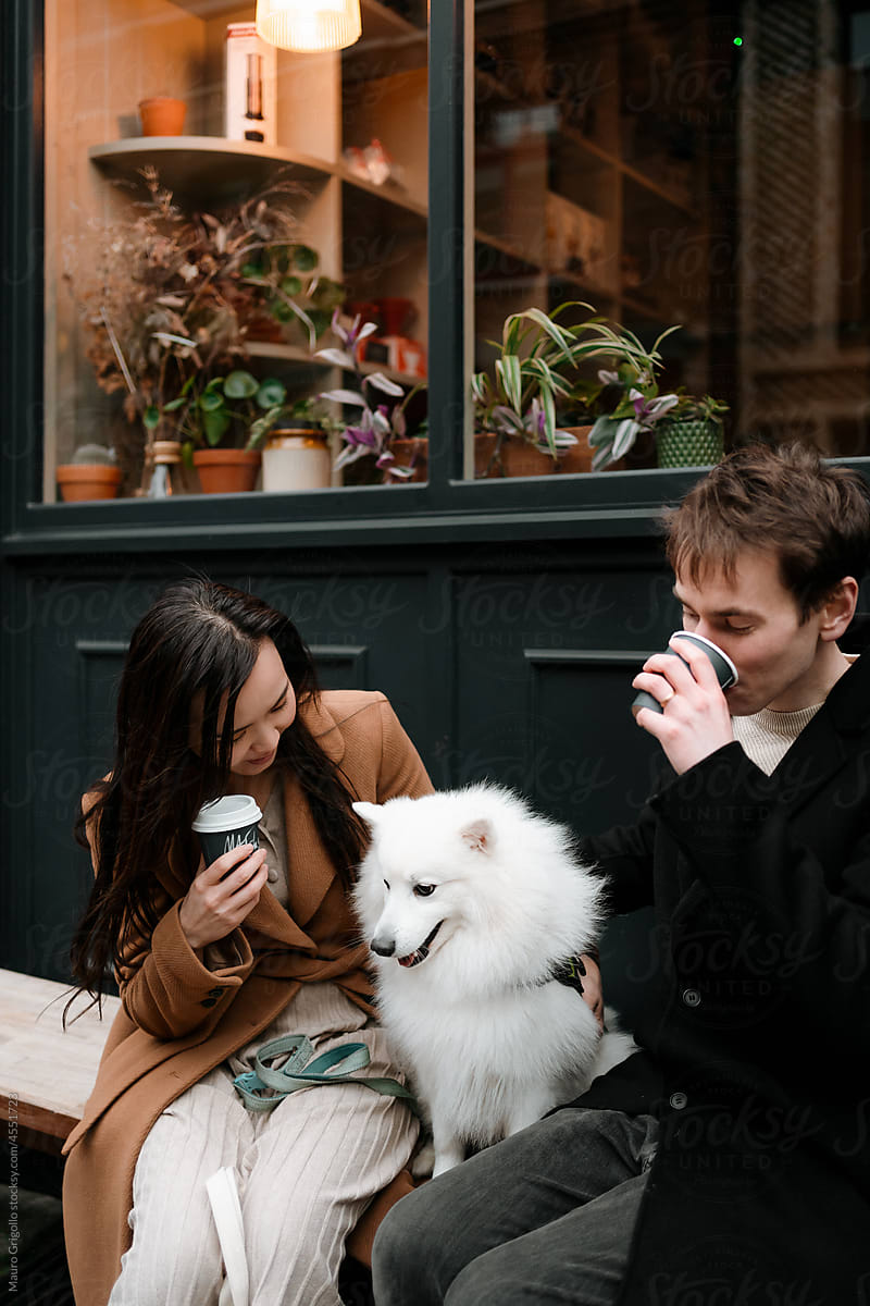 A couple drinks a coffee and have fun with the dog
