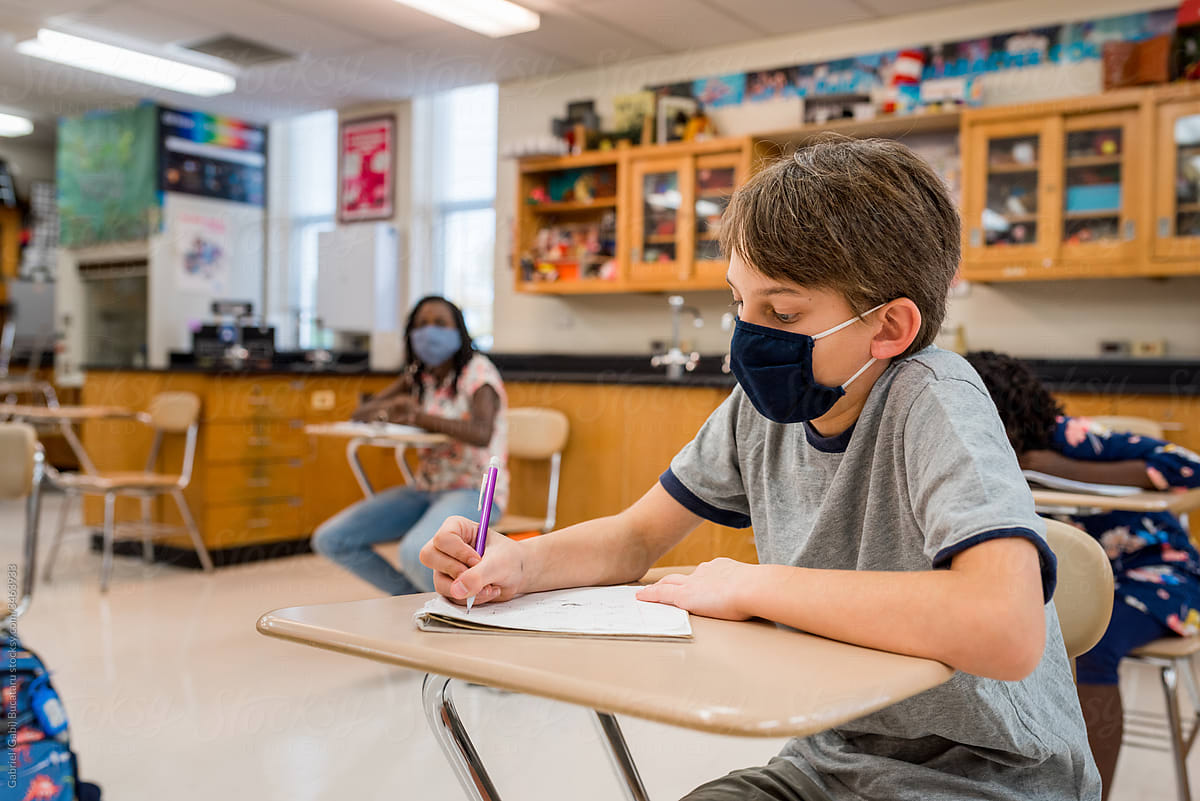 Boy with mask taking notes in a science class