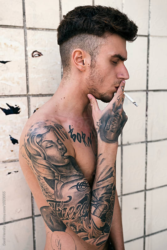 Side view of tattooed man smoking cigarette