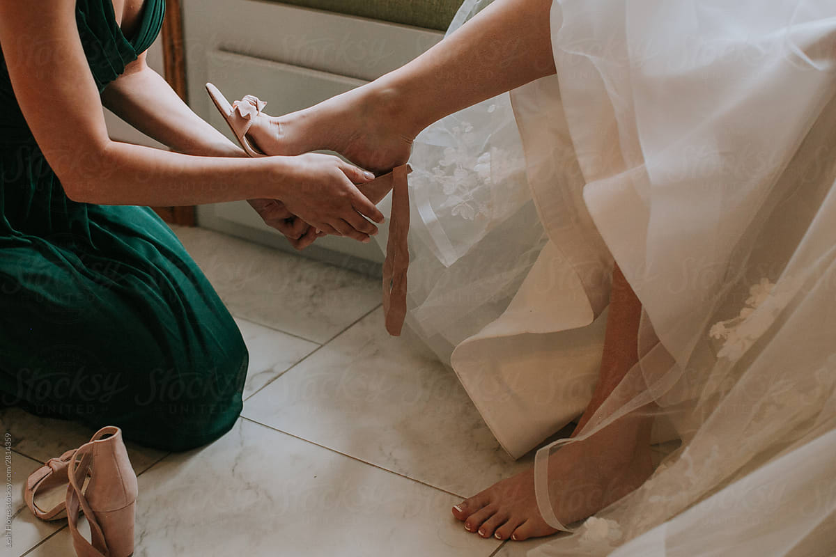 Bridesmaid Putting Shoes on Bride at Wedding