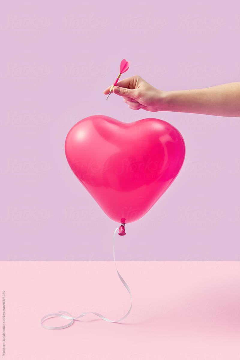 Woman piercing heart balloon
