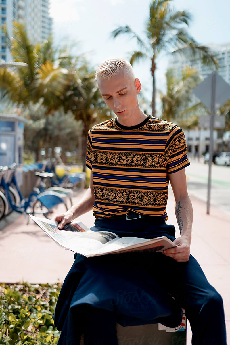 Stylish blond man reading newspaper outdoor in the City