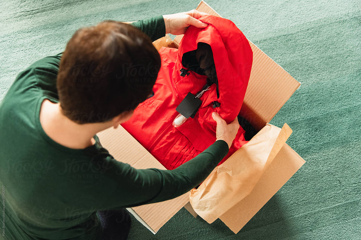 Middle-aged adult woman opening clothing delivery box