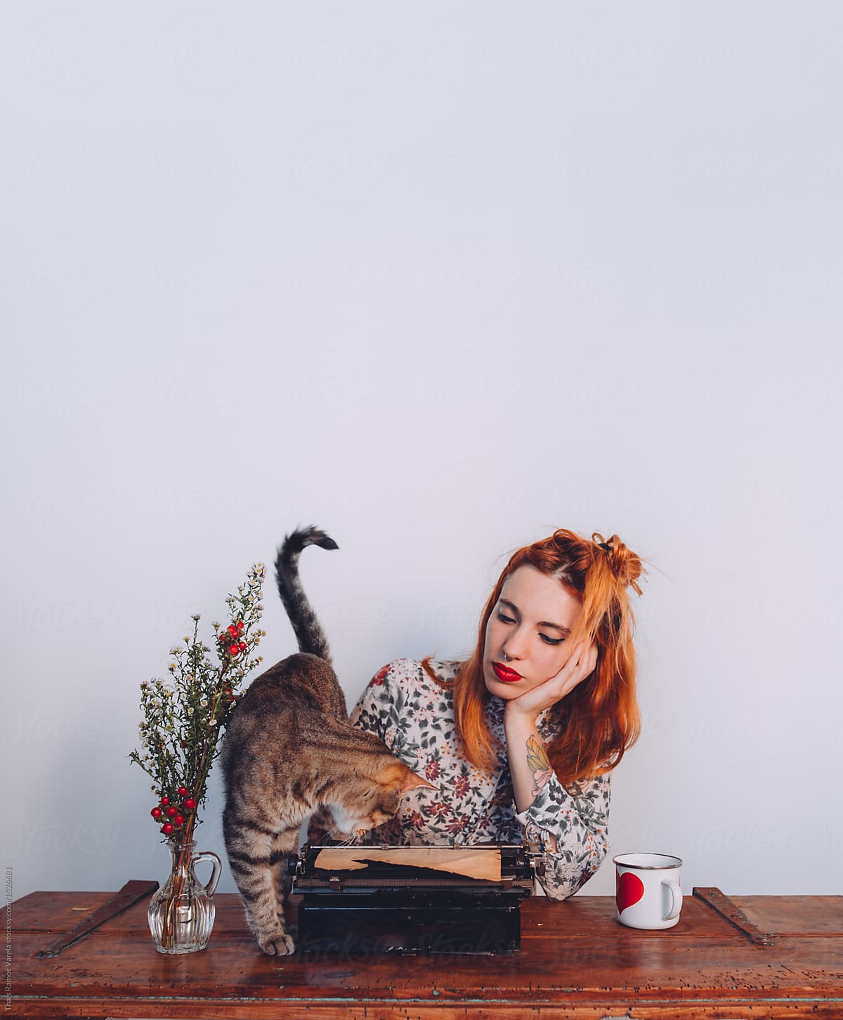 woman trying to work while her cat is playing whit the typewriter