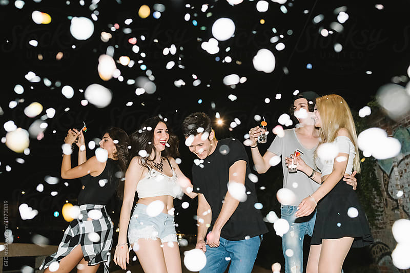 Group of friends dancing under a confetti rain in the disco