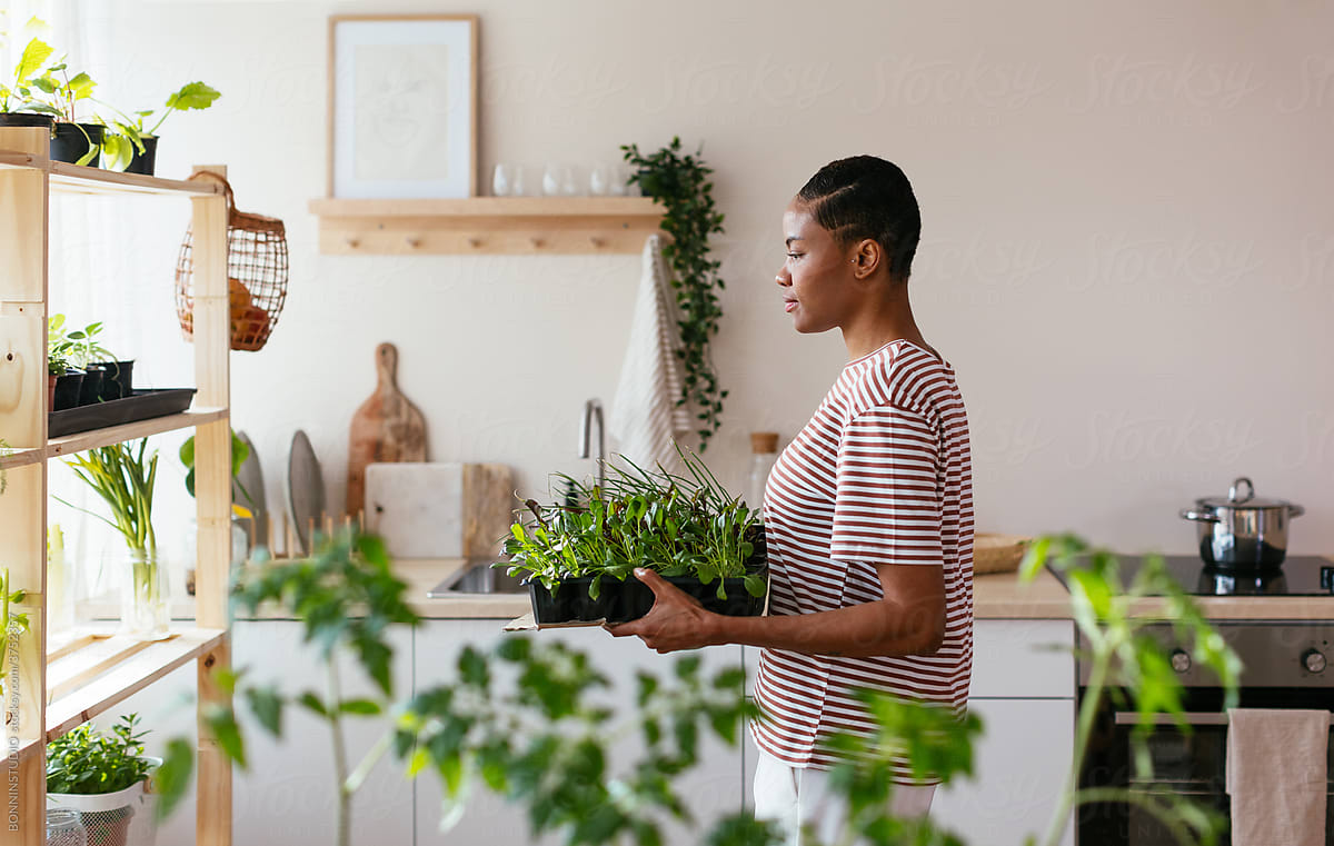 Black woman carrying sprouts in kitchen