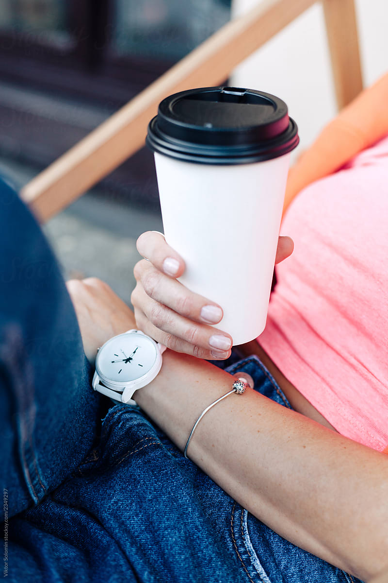 Street cafe closeup of woman\'s hands and watch with cup of hot coffee in her hands