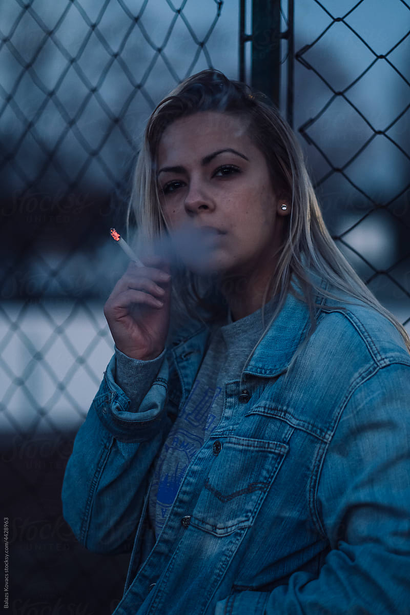 Woman smoking a cigarette on the street in the evening