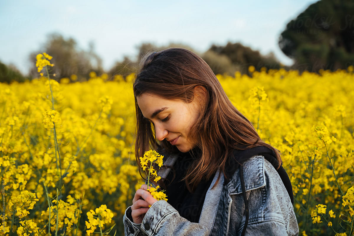 Happy Young woman in flowers field during sunset