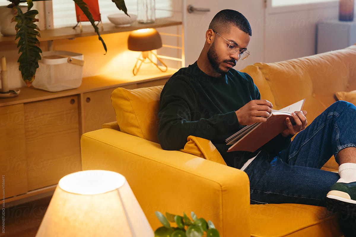Black man reading book on couch