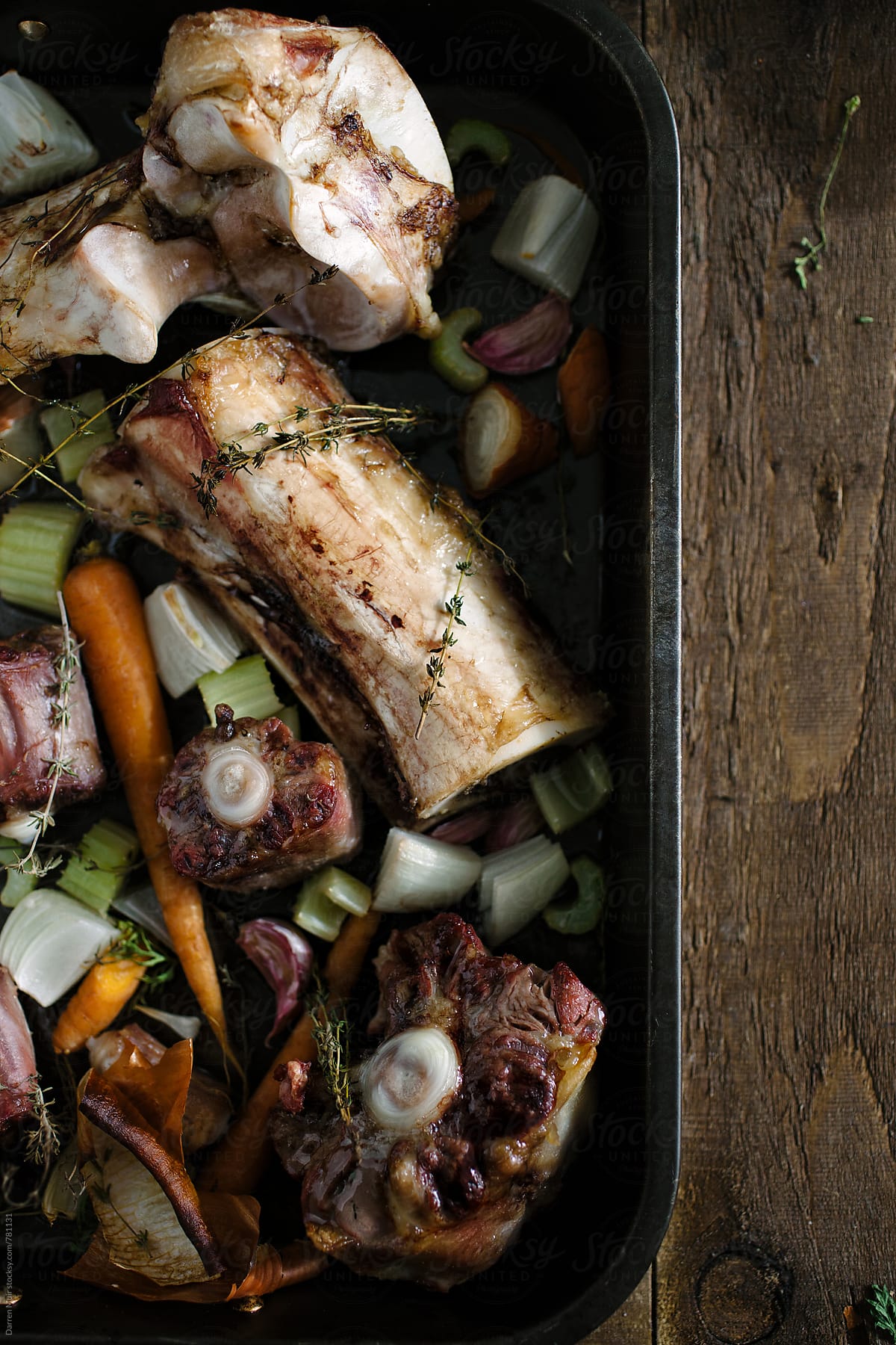 Roasted bones and vegetables in an oven tray.