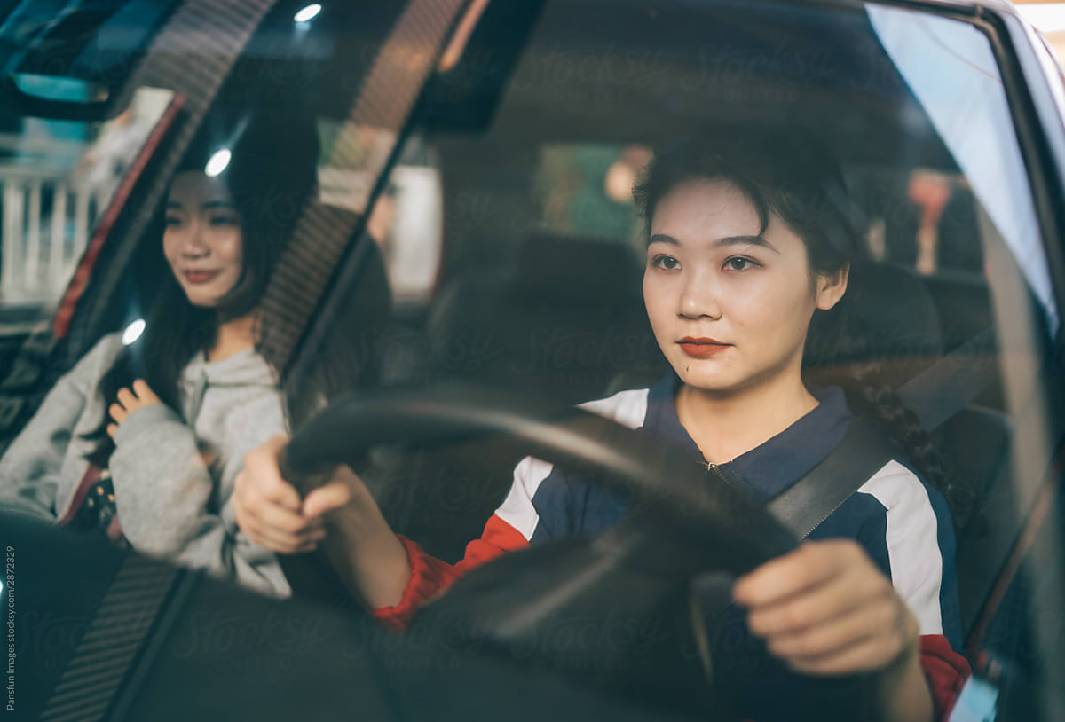 two young female friends drive in city