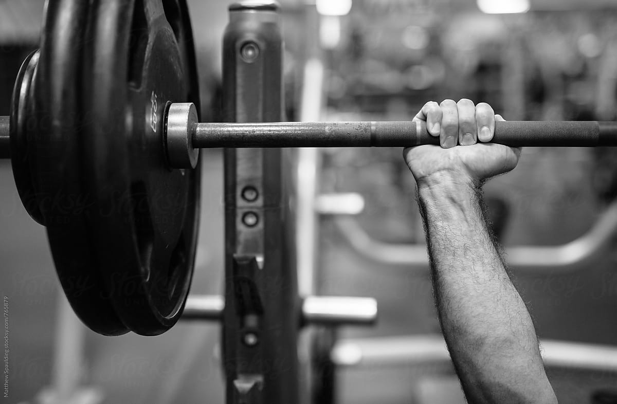 Man gripping bench press bar with weights at gym