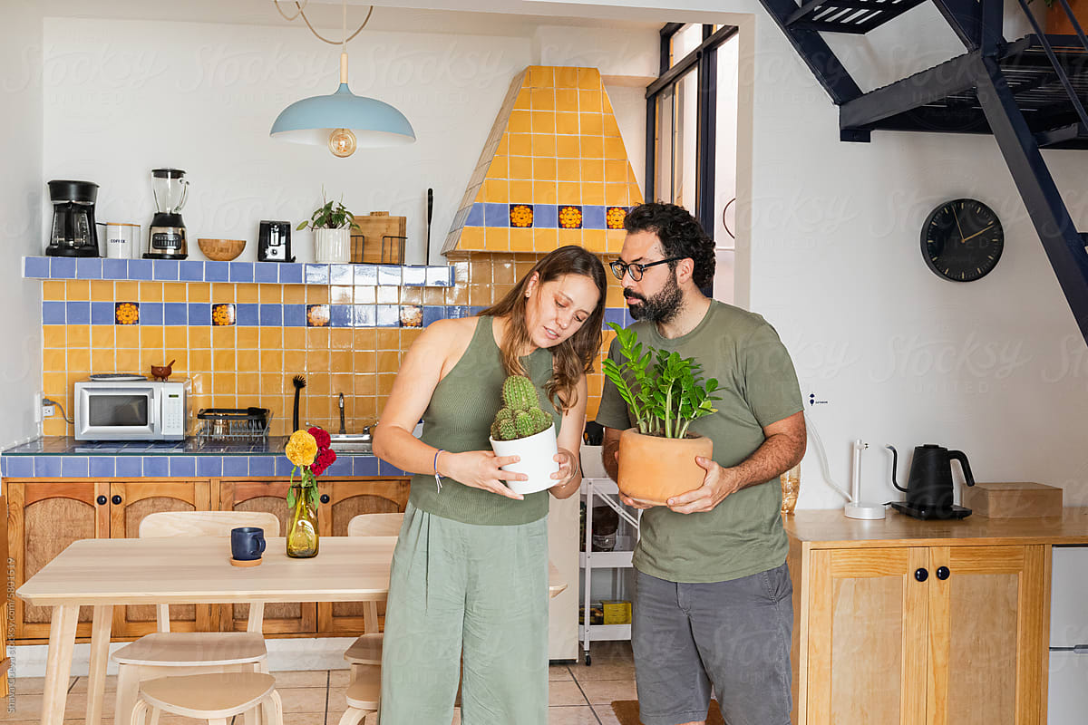 Couple holding pots with plants in a house