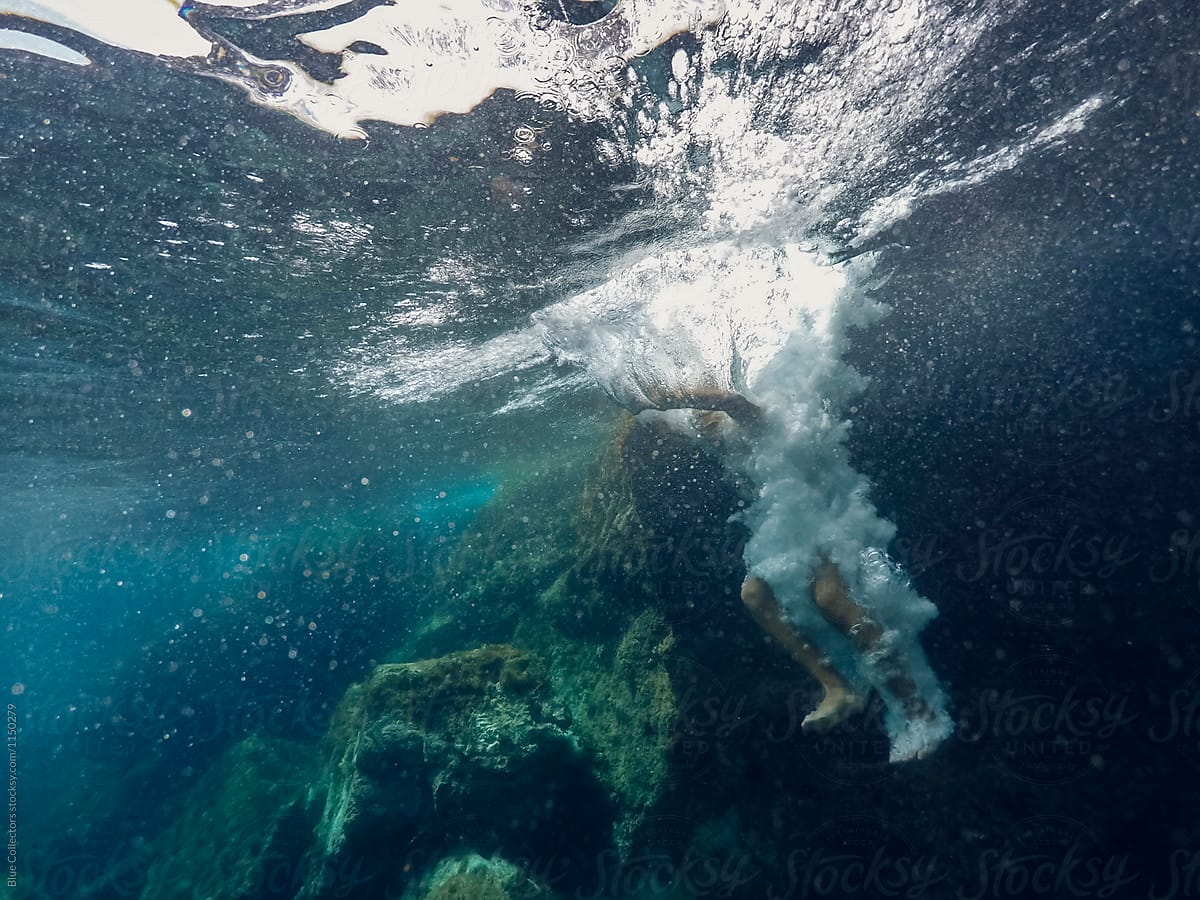 underwater view of a person falling down into the water