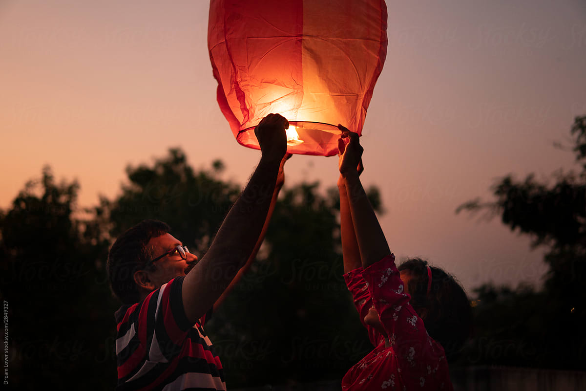 Father and daughter releasing Chinese lantern at night