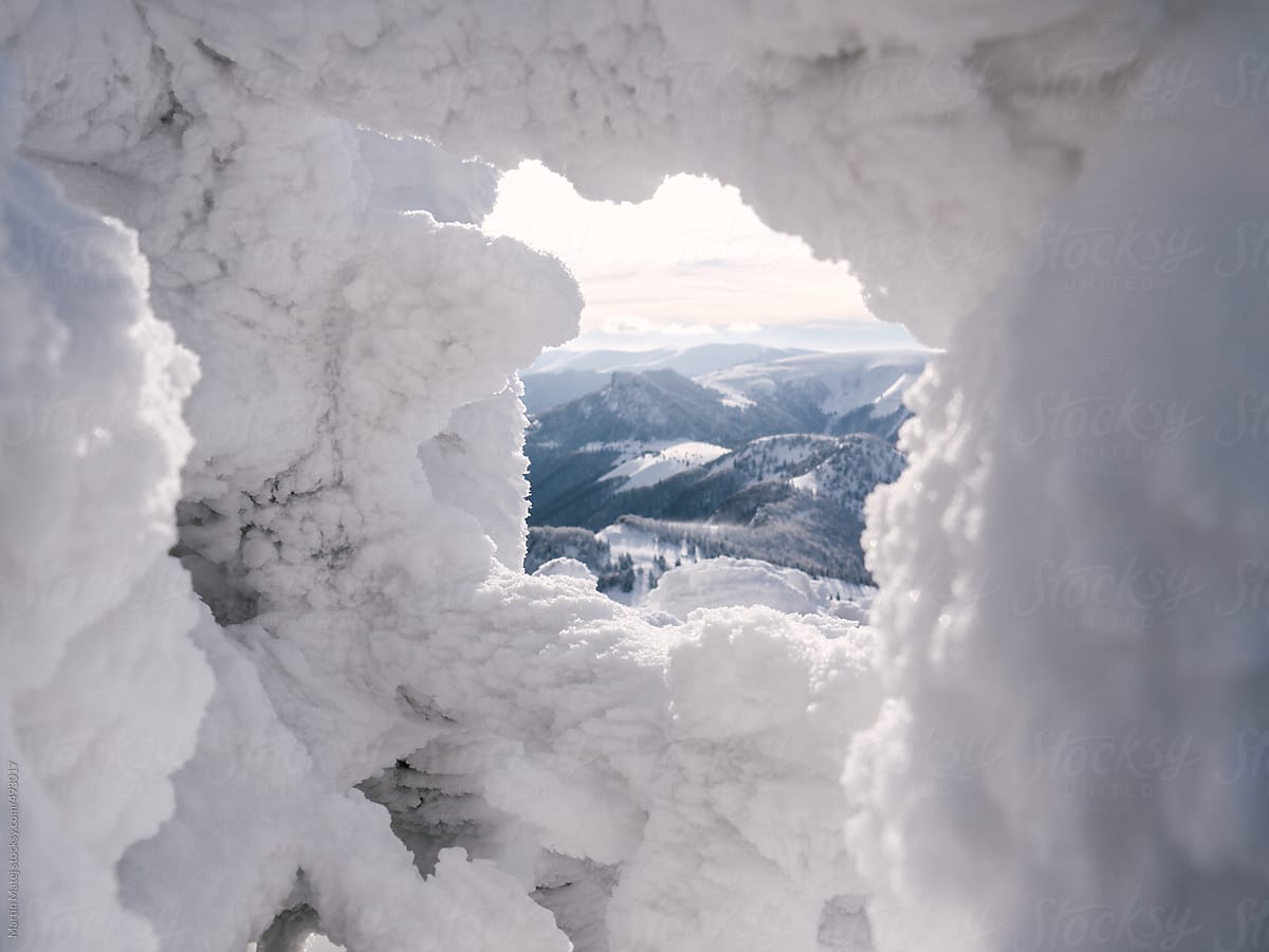 Mountains framed within hole in snow