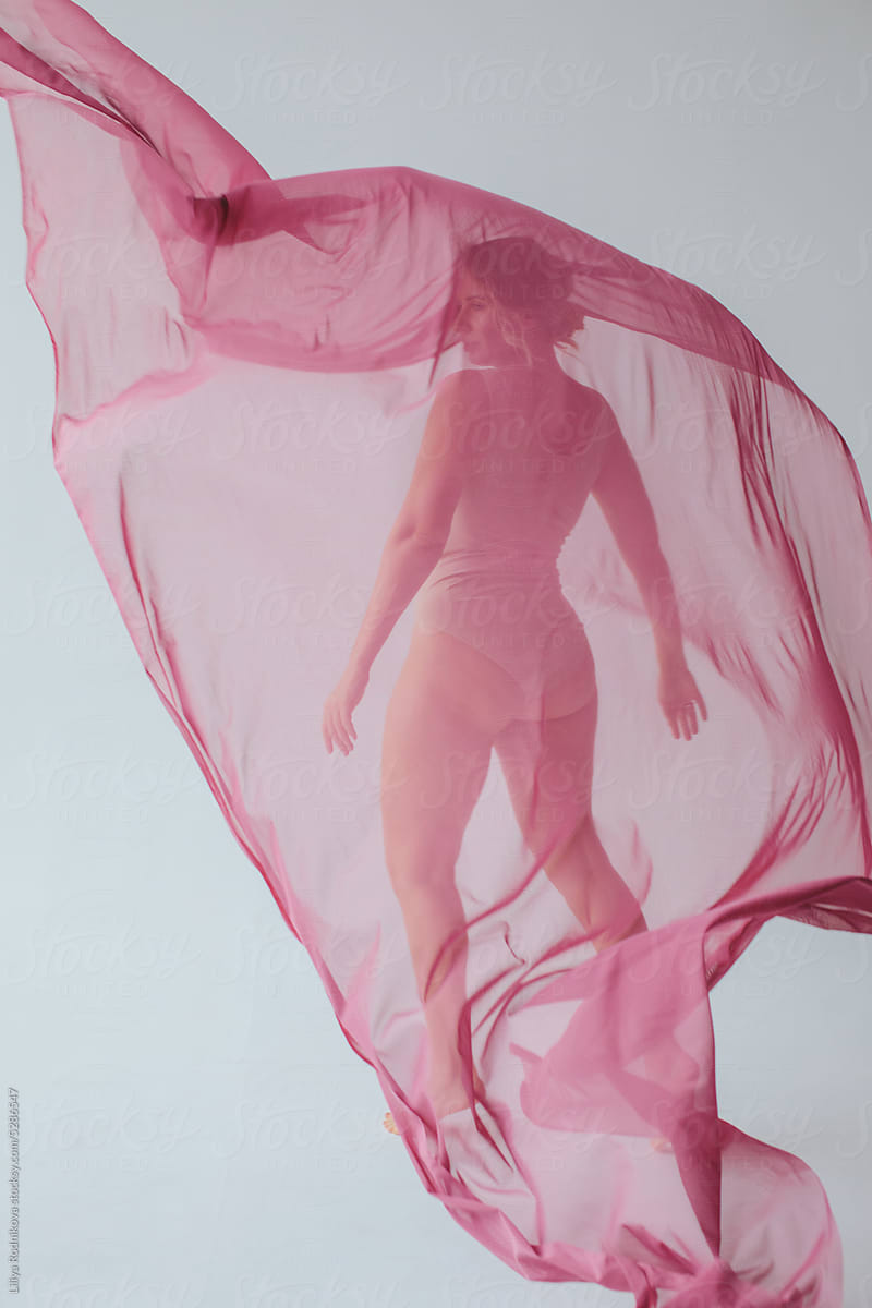 Curvy woman behind pink chiffon textile