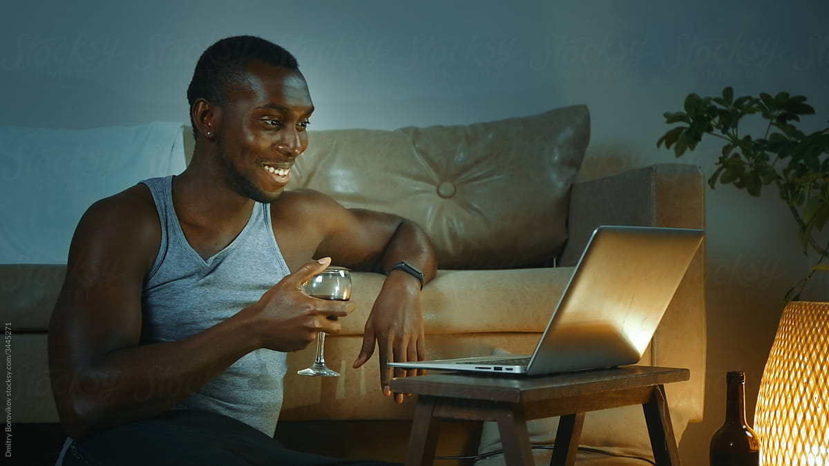 Man using laptop, drinking red wine