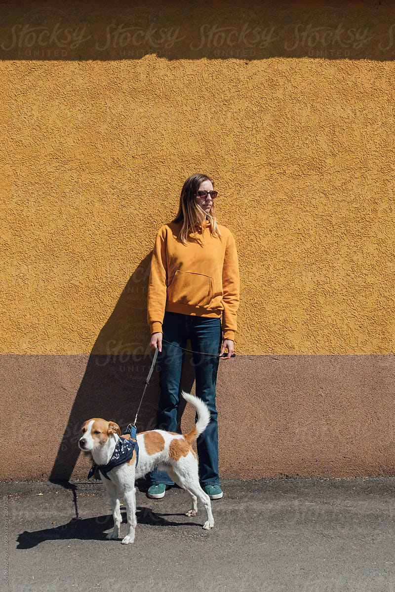 Woman in orange sweater walking a dog against the orange background