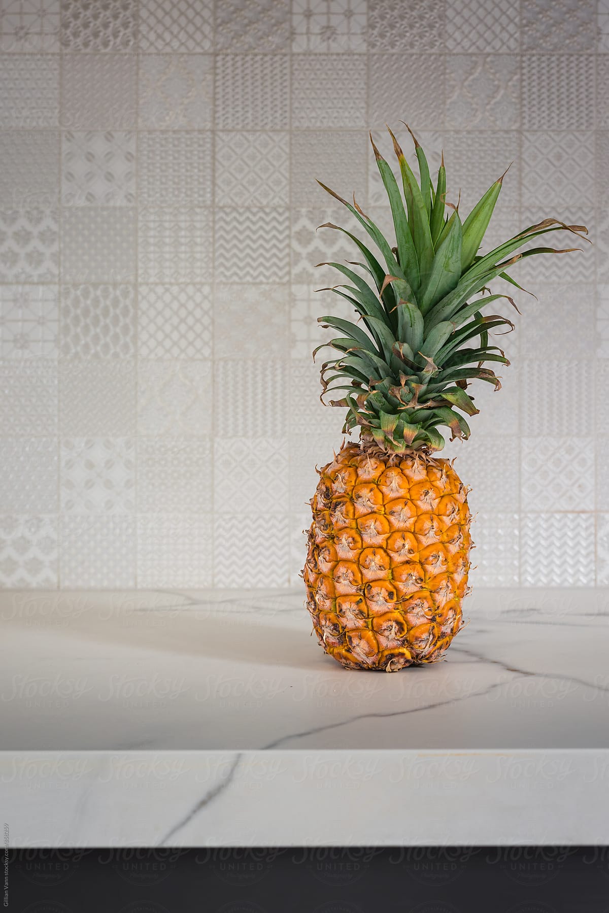 pineapple on a white countertop, with patterned tile background